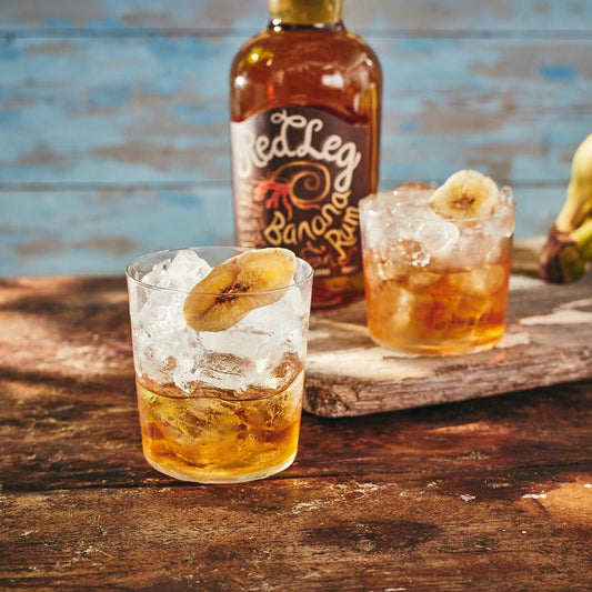 RedLeg Banana with 2 tumbler glasses filled with old fashioned cocktail on wooden surface