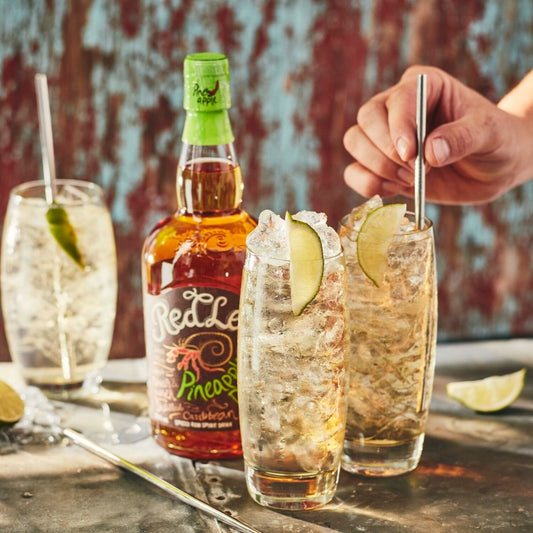 RedLeg Pineapple Rum with 3 tall glasses filled with rum, tonic and garnished with limes
